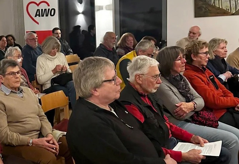 Menschen sitzen auf Stühlen in einem Saal und warten bis der Film losgeht
