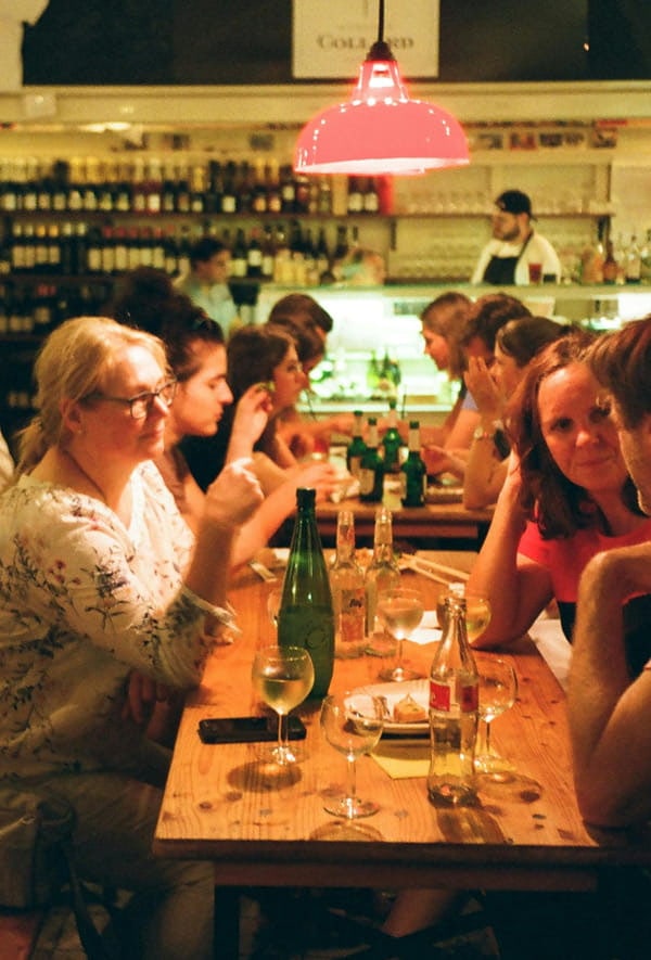 Menschen sitzen gemeinsam an einem langen Tisch in einem Restaurant und unterhalten sich in geselliger Atmosphäre